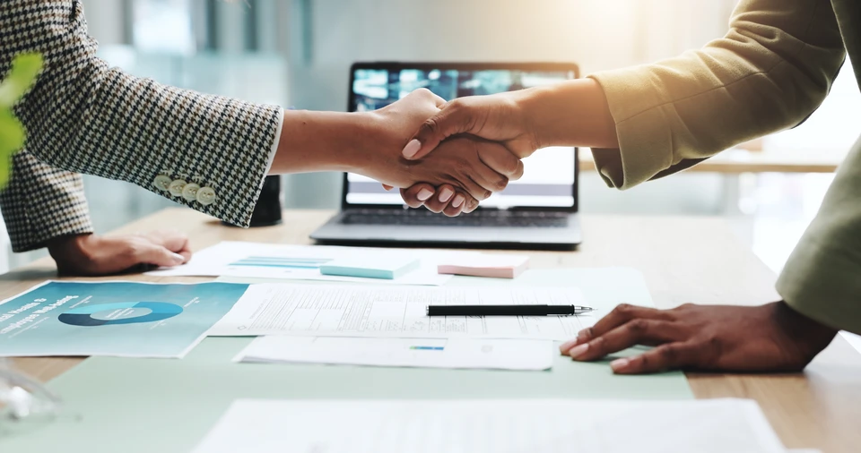 Couple de seniors souriants utilisant un ordinateur portable dans un salon moderne, femme en cardigan orange et homme en chemise bleue, interaction chaleureuse devant l'écran