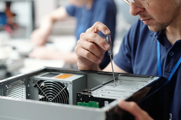 Femme d'affaires en chemise blanche travaillant sur ordinateur portable dans bureau moderne avec fauteuil cuir beige
