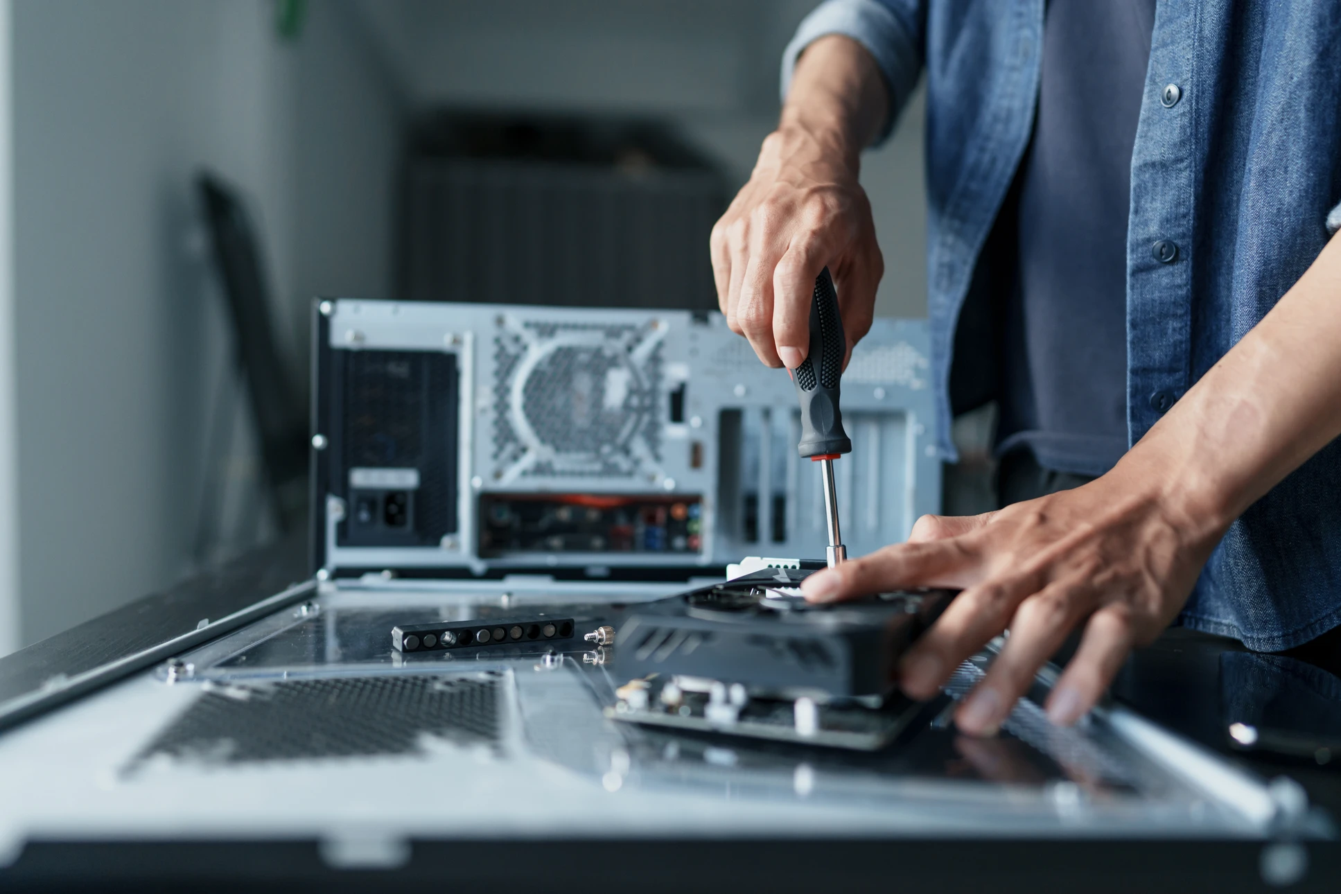 Personne en chemise blanche travaillant sur ordinateur portable dans un environnement de bureau à domicile